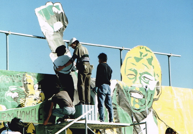 _ Preparations begin: Crew members of the rally’s organizing team hoist the image of Mandela’s raised fist as part of the stage backdrop for the day’s events.  _ Preparations begin: Crew members of the rally’s organizing team hoist the image of Mandela’s raised fist as part of the stage backdrop for the day’s events.