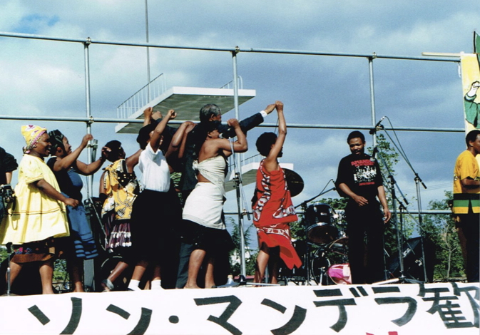 _ It is finally time for the man himself to speak, and with great whooping and cheering by the South African members of Amandla, Nelson Mandela is jubilantly led to center stage.  _ It is finally time for the man himself to speak, and with great whooping and cheering by the South African members of Amandla, Nelson Mandela is jubilantly led to center stage.