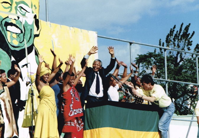 _ The audience at the stadium gives the guest of honor a rousing welcome and standing ovation, as Mandela and members of Amandla wave back to the ecstatic crowd.  _ The audience at the stadium gives the guest of honor a rousing welcome and standing ovation, as Mandela and members of Amandla wave back to the ecstatic crowd.